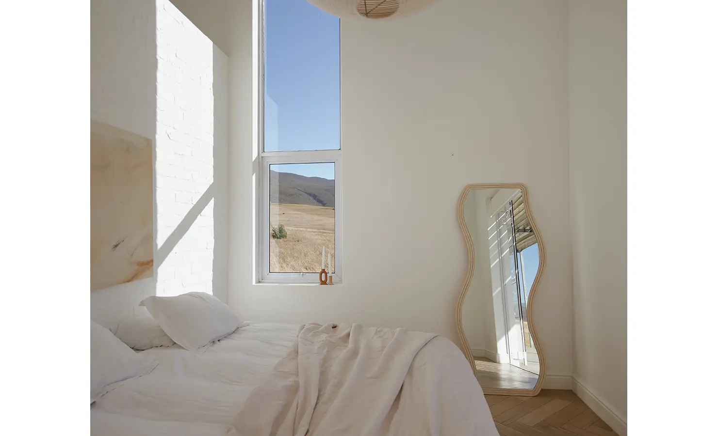Perfect Hideaways: Minimalist bedroom with high windows, soft neutral bedding, and a full-length wave mirror, Thuúla Haven, Hemel-en-Aarde.