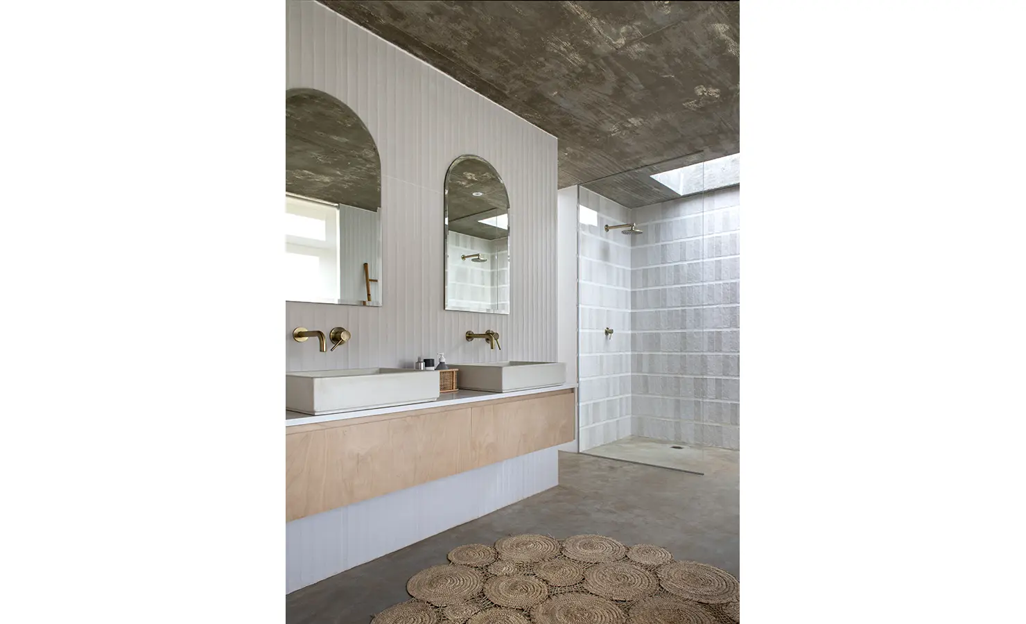 Perfect Hideaways: Double vanity bathroom with arch mirrors and walk-in shower beneath a concrete ceiling and skylight, Thuúla Haven, Hemel-en-Aarde.