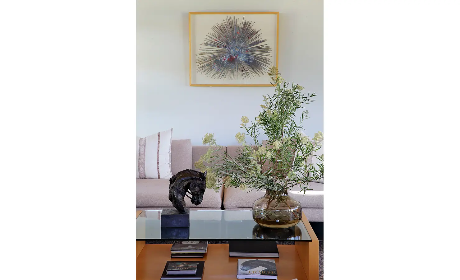 Perfect Hideaways: A close-up of a glass coffee table with a horse sculpture, a vase of wild greenery, and curated books, reflecting the equestrian-inspired elegance of the space. Equestrian House, Stellenbosch.