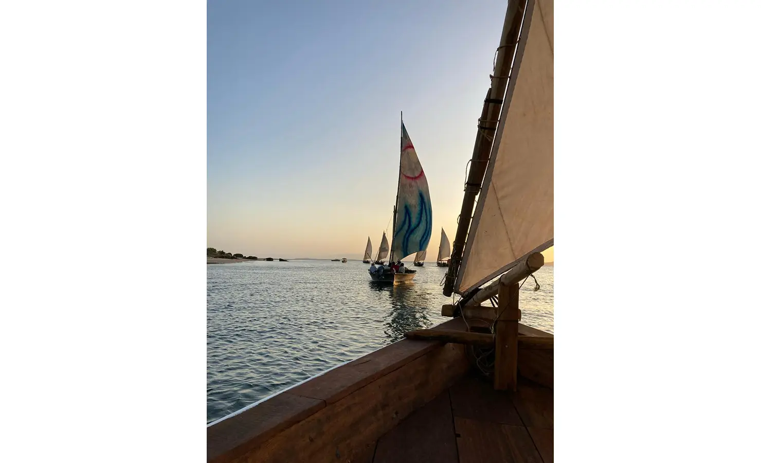 Perfect Hideaways: A tranquil view of traditional dhow boats sailing during sunset, captured from the deck of another boat. Shela Beach House, Lamu.