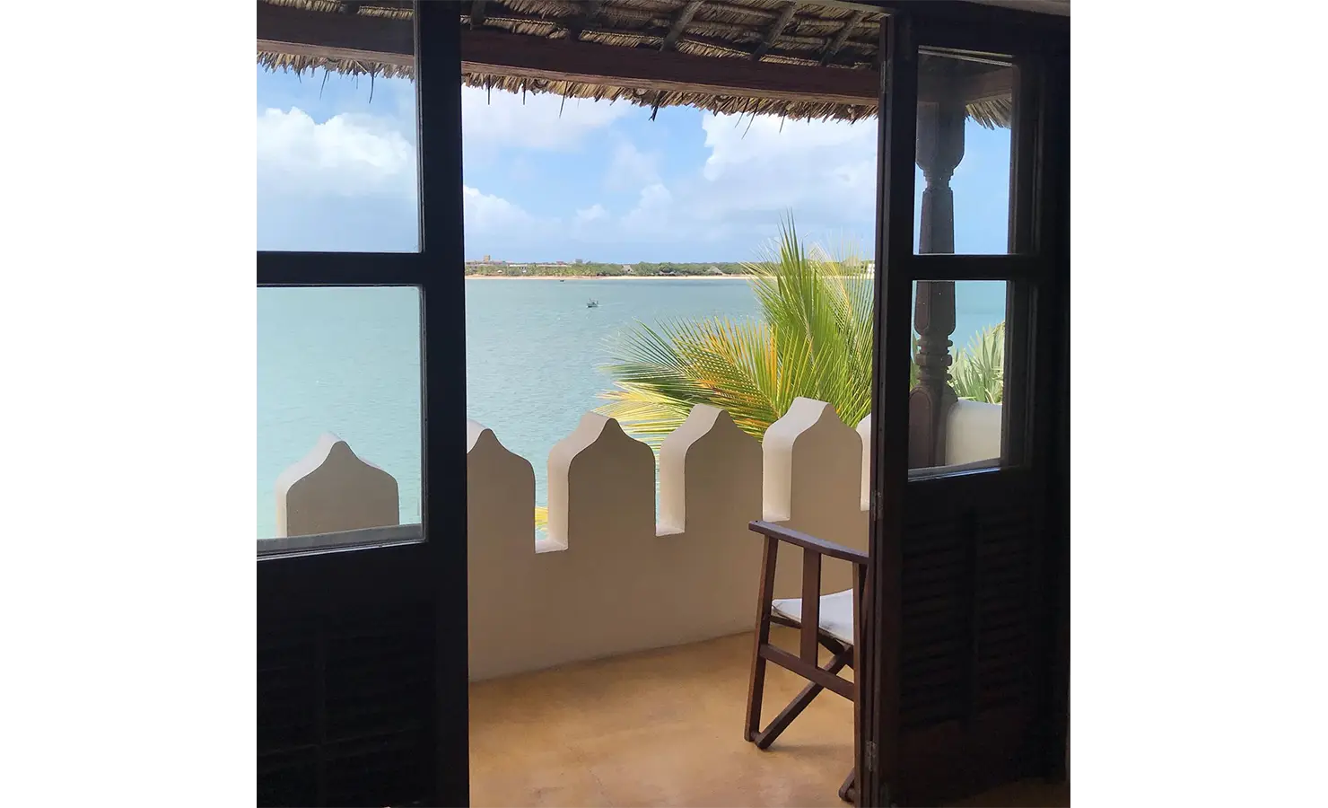Perfect Hideaways: A private balcony with a traditional Swahili railing, offering panoramic views of the calm ocean waters. Shela Beach House, Lamu.