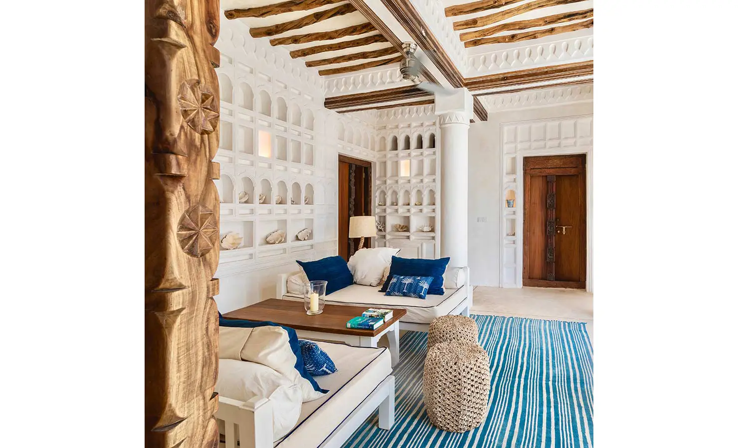 Perfect Hideaways: A bright and airy dining room with a long wooden table, white chairs, and arched windows, blending modern and traditional Swahili architectural styles. The Kasbah, Lamu.
