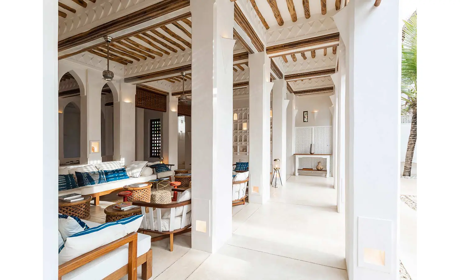 Perfect Hideaways: A light-filled lounge area with traditional Swahili architecture, wooden beams, and comfortable seating adorned with patterned cushions. The Kasbah, Lamu.