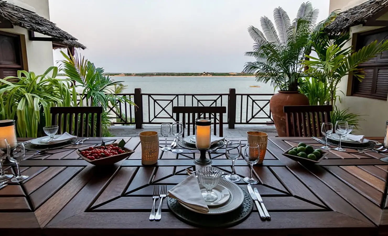 erfect Hideaways: A beautifully set dining table on a veranda with ocean views, surrounded by lush tropical plants and Swahili design elements. Shela Beach House, Lamu.