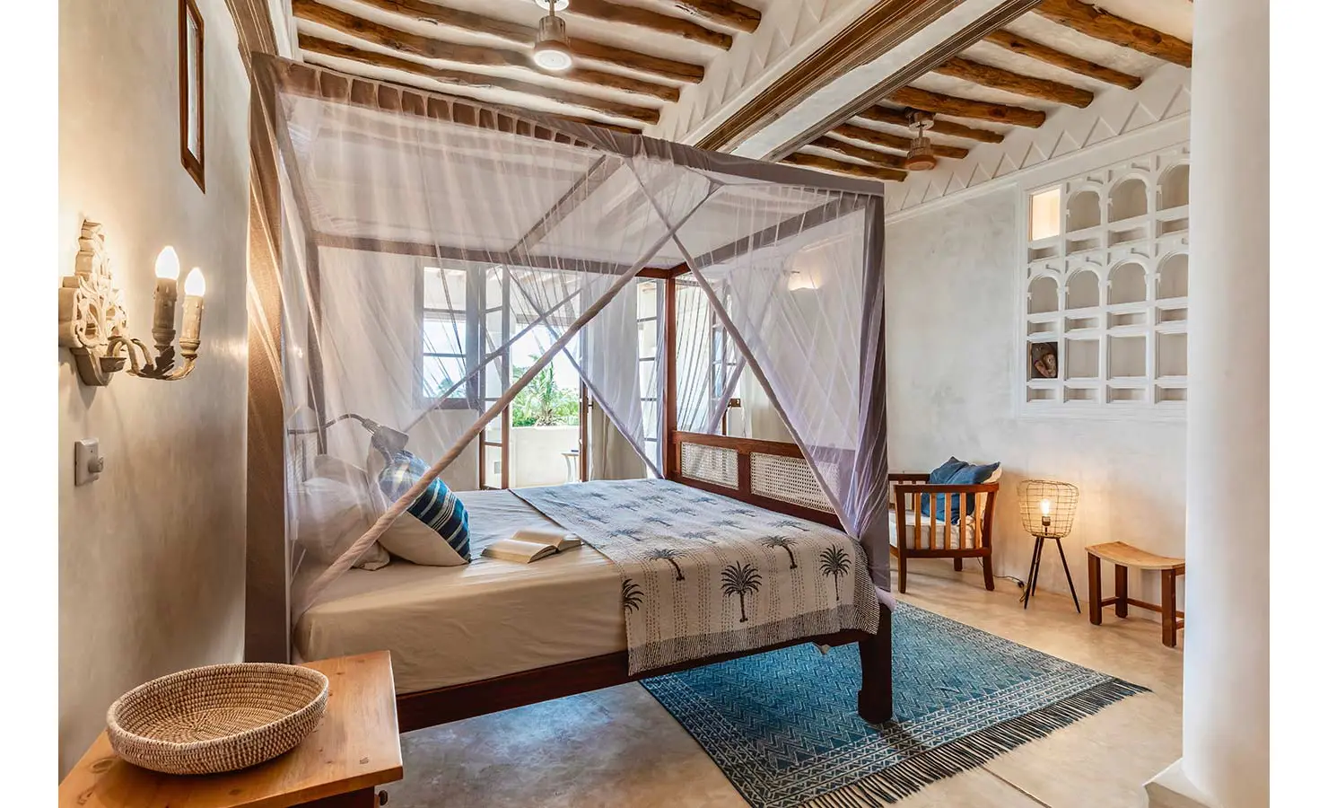 Perfect Hideaways: A serene bedroom featuring a four-poster bed with a mosquito net, soft lighting, and wooden detailing, exuding an elegant coastal charm. The Kasbah, Lamu.