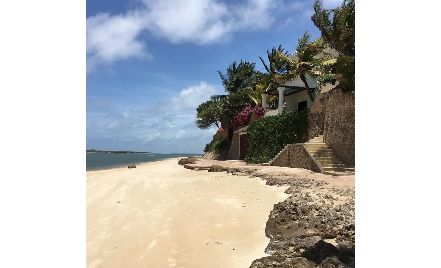 Perfect Hideaways: A picturesque beachfront with soft sand, vibrant bougainvillaea, and steps leading to a tropical villa. Shela Beach House, Lamu.