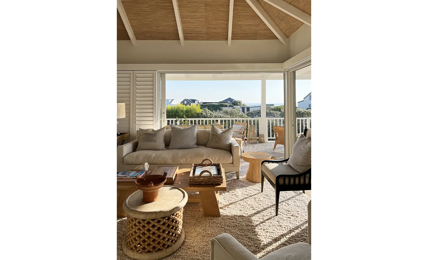 Perfect Hideaways: A serene coastal lounge with plush seating and soft natural tones, opening onto a sun-drenched deck. The perfect balance of comfort and laid-back beachside luxury. Sunset Cove, Kommetjie.