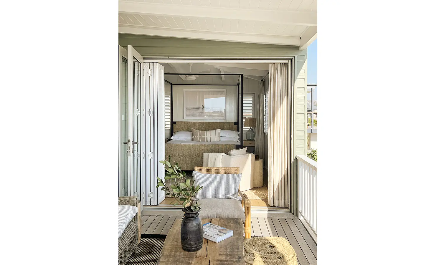 Perfect Hideaways: A serene bedroom seamlessly opening onto a covered deck, featuring a textured headboard and soft neutral furnishings. A peaceful retreat with ocean breezes drifting through. Sunset Cove, Kommetjie.