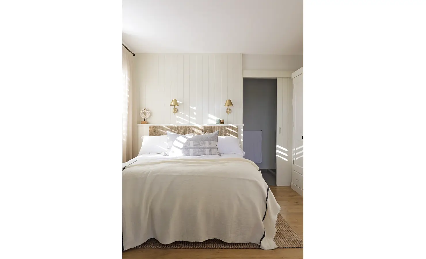 Perfect Hideaways: A tranquil bedroom with soft, layered bedding and natural textures, illuminated by golden afternoon light filtering through wooden shutters. Sunset Cove, Kommetjie.