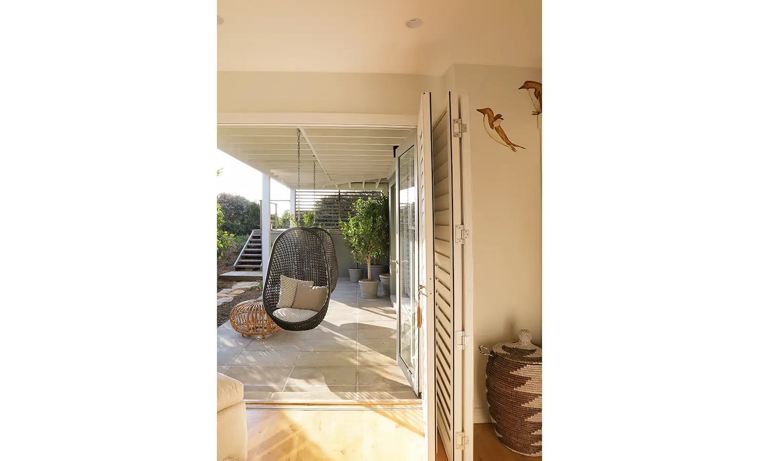 Perfect Hideaways: A peaceful outdoor nook featuring a woven hanging chair, earthy textures, and lush greenery—an inviting spot to unwind. Sunset Cove, Kommetjie.