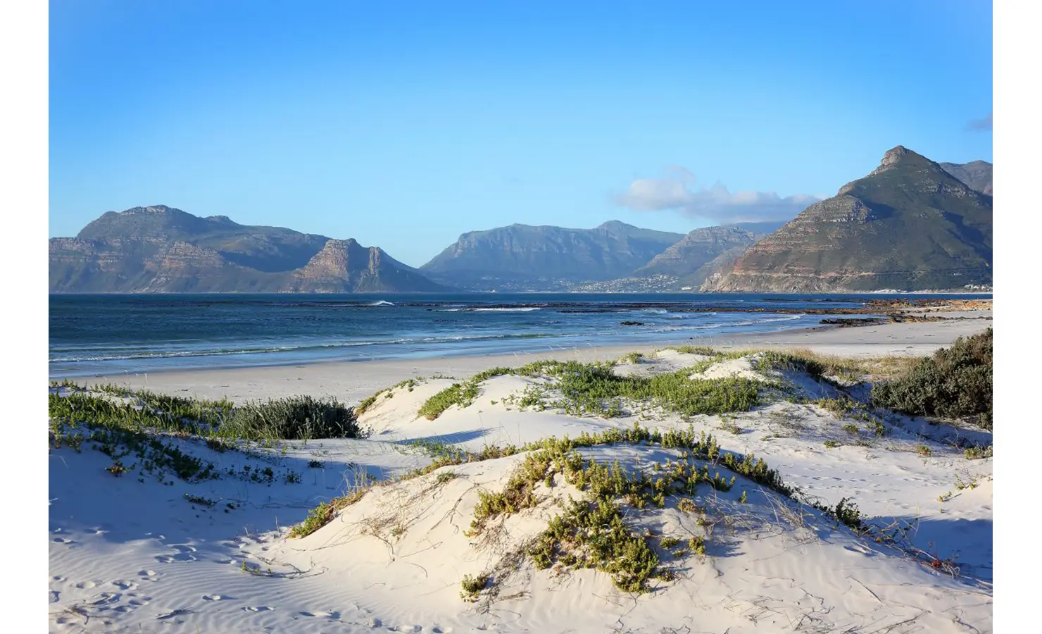 Perfect Hideaways: A pristine stretch of sandy beach with rolling dunes and dramatic mountain peaks in the distance. A coastal paradise where land meets sea in perfect harmony. Sunset Cove, Kommetjie.