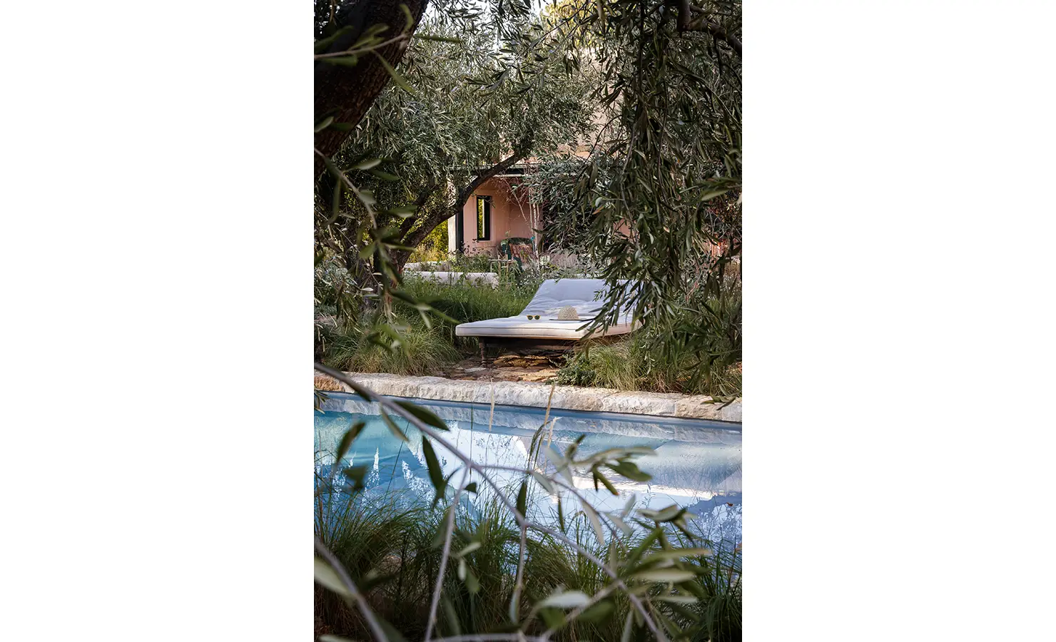Perfect Hideaways: A cosy lounging area beside a crystal-clear pool, framed by olive trees and soft greenery, with a glimpse of the villa in the background. Sterrekopje, Franschhoek.