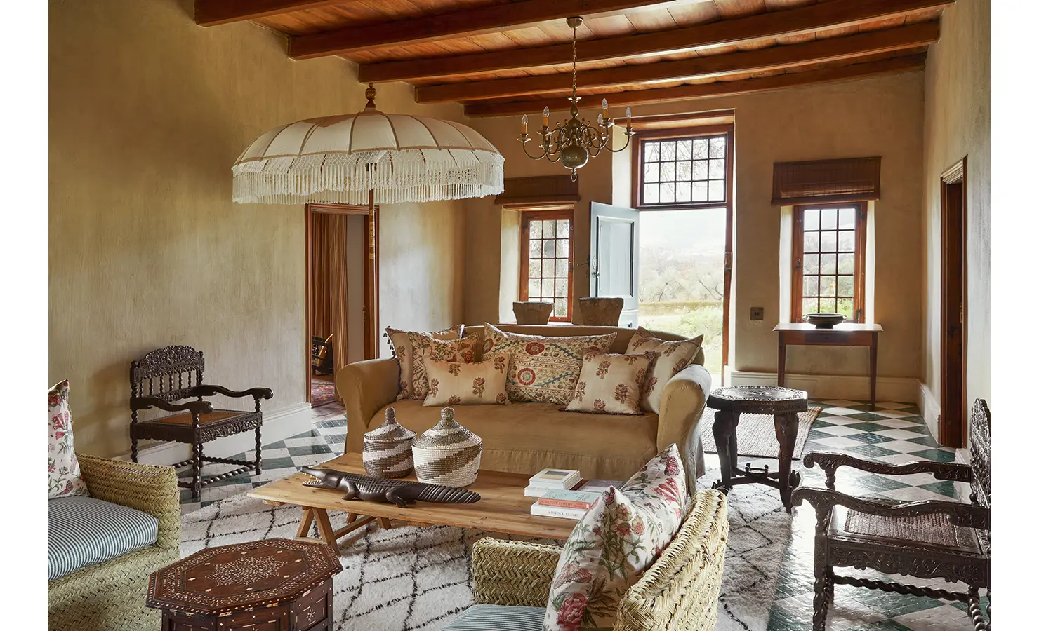 Perfect Hideaways: A tastefully decorated living room with a blend of rustic and vintage furnishings, featuring a chandelier, floral cushions, and large windows. Sterrekopje, Franschhoek.