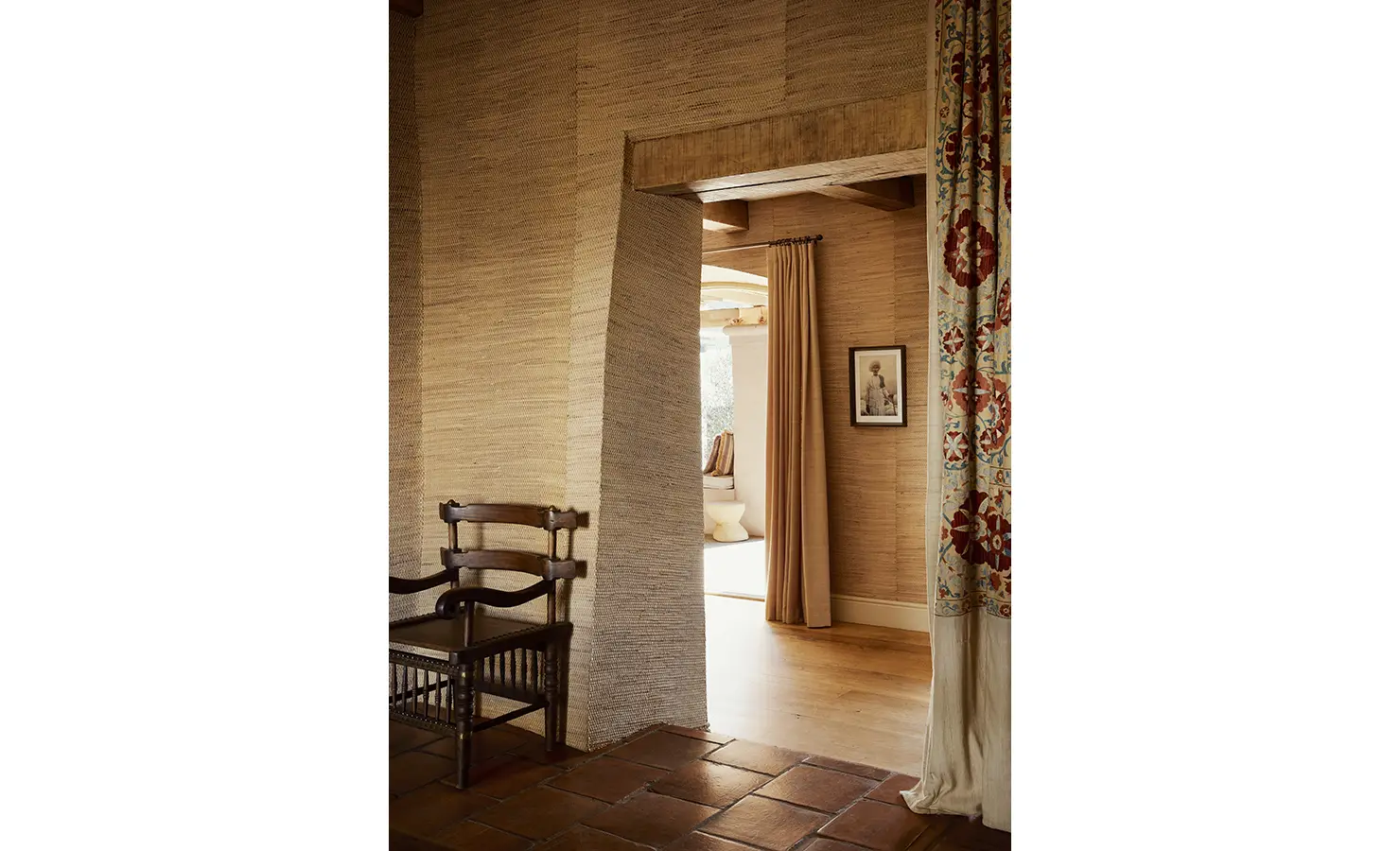 Perfect Hideaways: A hallway with textured walls and a classic wooden chair, leading to a softly lit room with a view of an outdoor area. Sterrekopje, Franschhoek.
