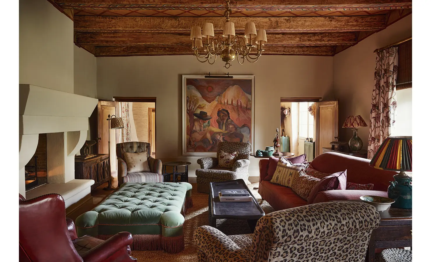 Perfect Hideaways: A cosy living room featuring eclectic furnishings, patterned chairs, a tufted ottoman, and a bold artwork under a rustic ceiling with a chandelier. Sterrekopje, Franschhoek.