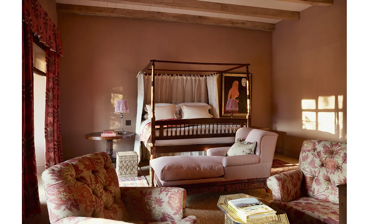 Perfect Hideaways: A bedroom with a four-poster bed, floral upholstery, and a soft pink colour palette bathed in golden sunlight. Sterrekopje, Franschhoek.