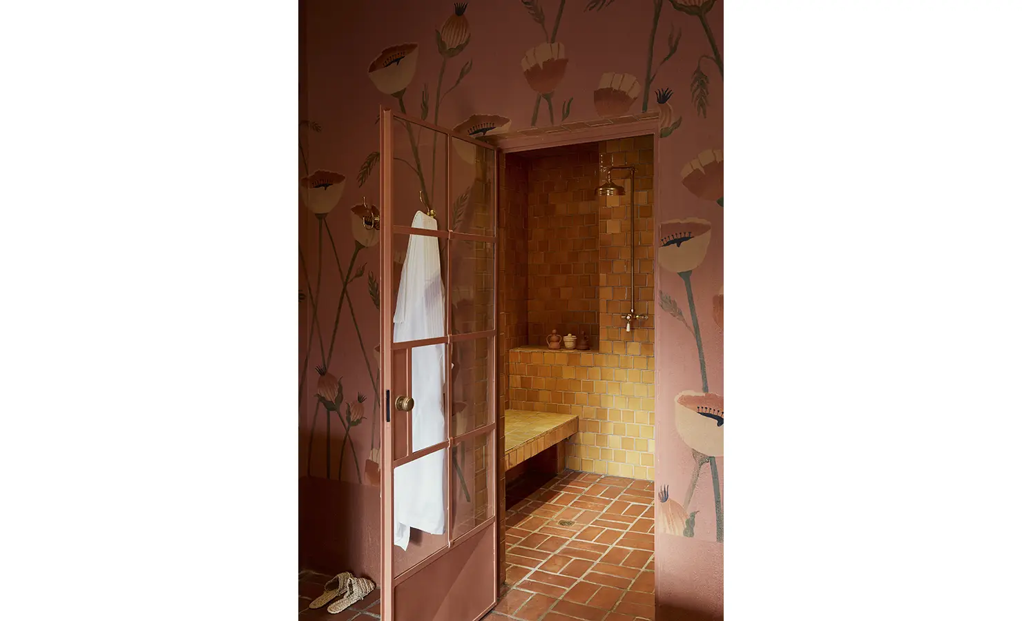 Perfect Hideaways: A shower area with a glass door, terracotta tiles, and floral-patterned walls, offering a warm, earthy ambience. Sterrekopje, Franschhoek.