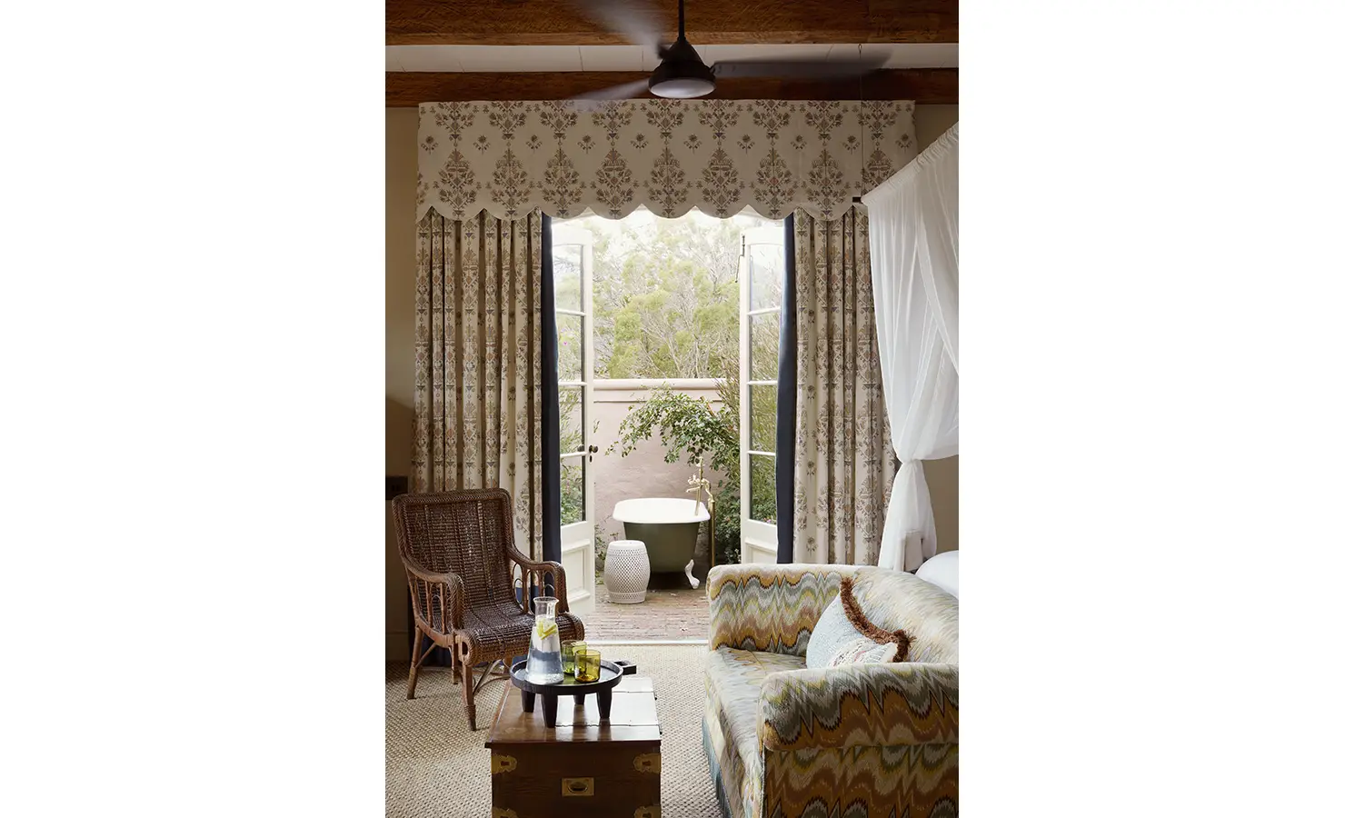 Perfect Hideaways: A serene sitting area with patterned upholstery, opening onto a private courtyard with a freestanding outdoor tub. Sterrekopje, Franschhoek.