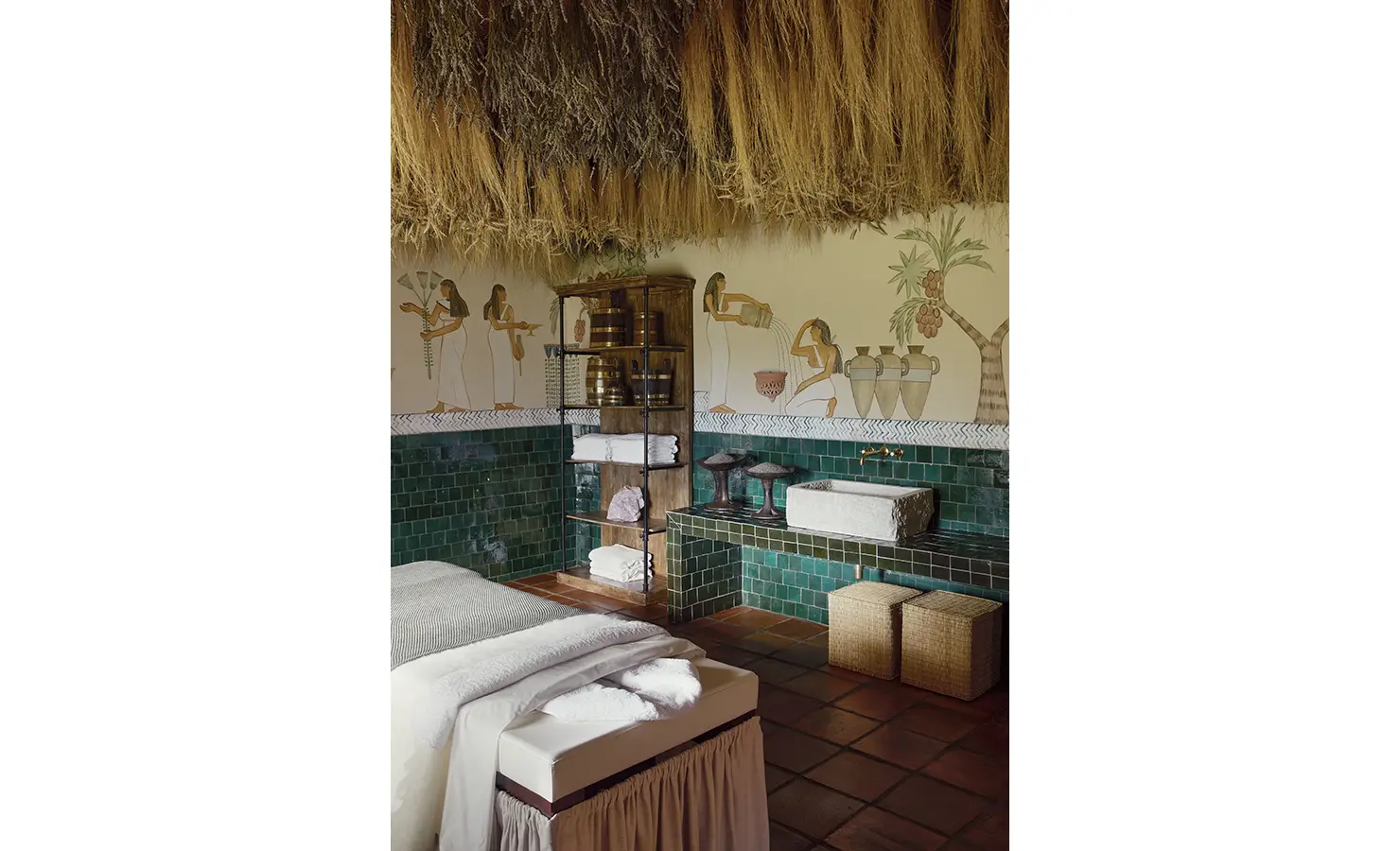 Perfect Hideaways: A spa room adorned with Egyptian-inspired murals, green tiles, and a cosy treatment bed under a thatched ceiling. Sterrekopje, Franschhoek.