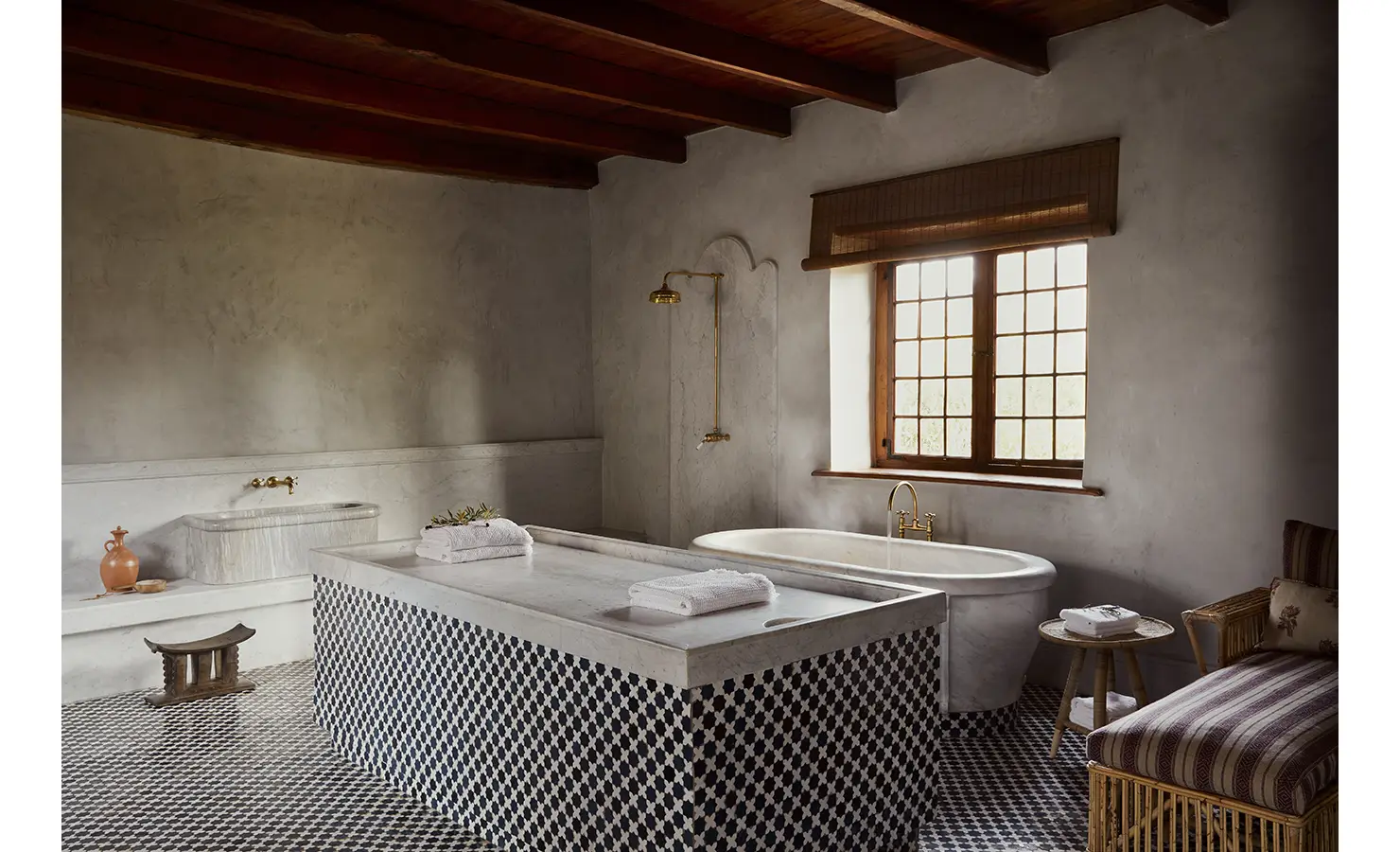 Perfect Hideaways: A spacious bathroom with a freestanding tub, patterned tiles, and a central marble wash station under a beamed ceiling. Sterrekopje, Franschhoek.