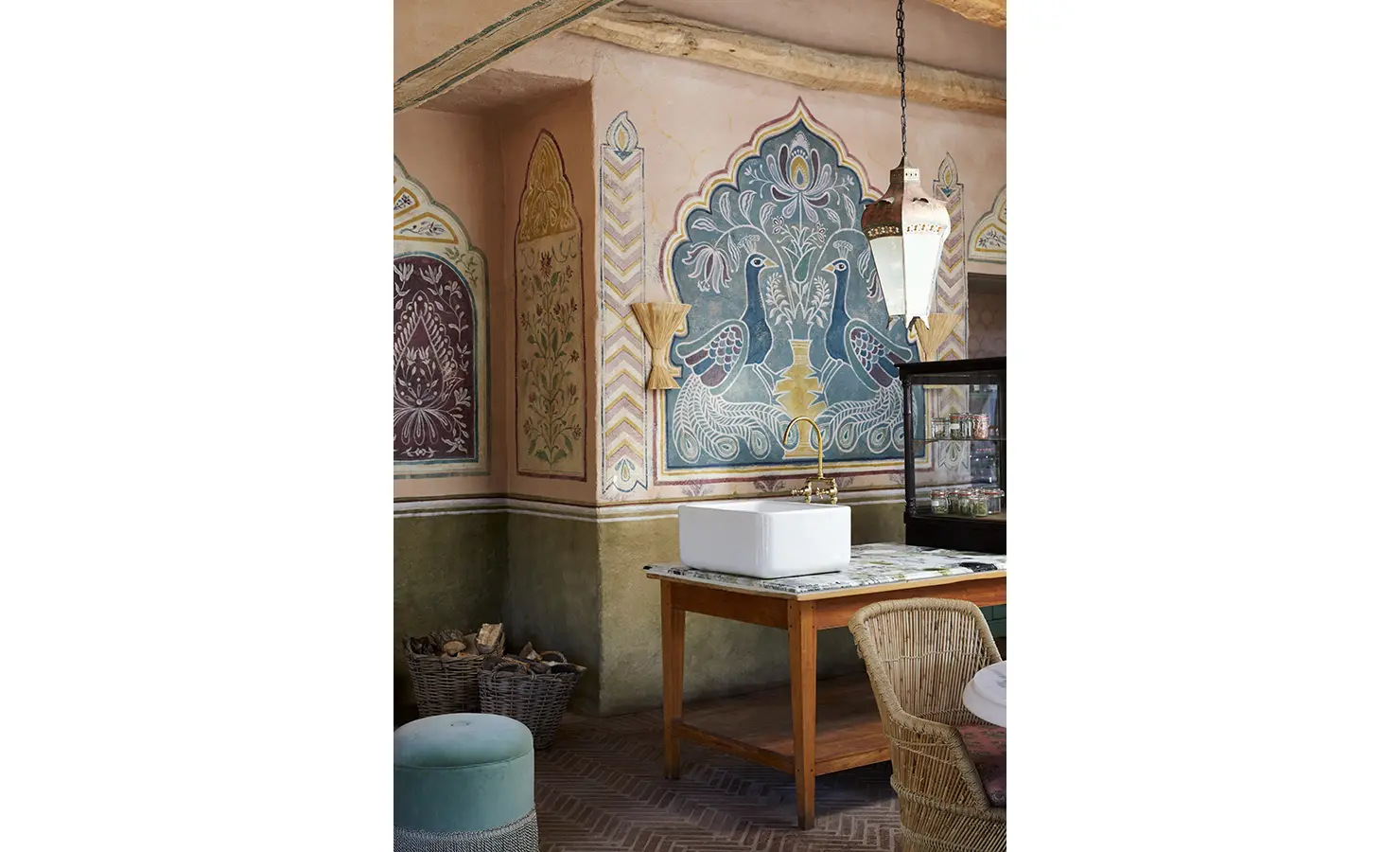 Perfect Hideaways: A vibrant interior with hand-painted wall art, wicker furniture, and a central sink on a wooden table. Sterrekopje, Franschhoek.