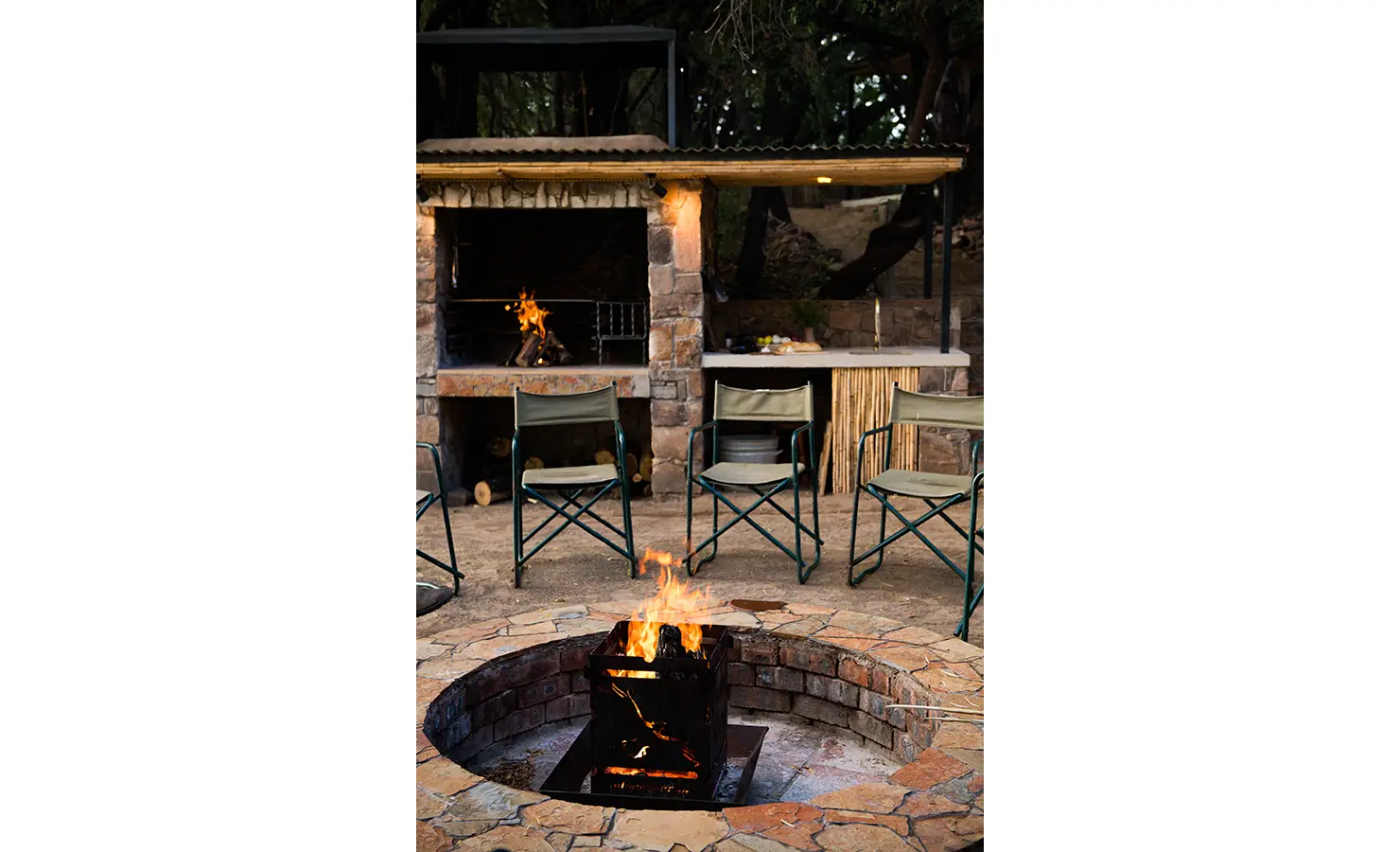 Perfect Hideaways: A cosy firepit flickers under the evening sky, surrounded by canvas chairs and a rustic braai area, creating the perfect atmosphere for storytelling and relaxation. Orange River House, Hopetown.