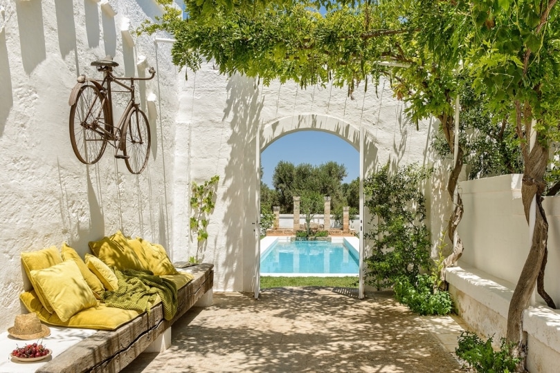 Courtyard with mustard cushions and fresh cherries under the wisteria at Masseria Narducci, Northern Puglia, overlooking the pool