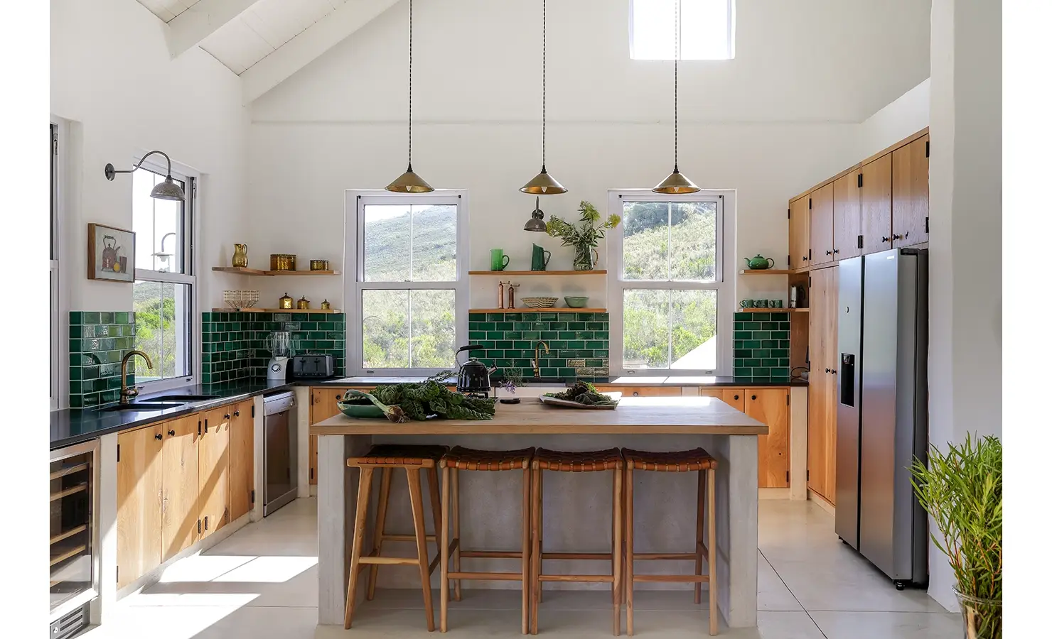 Buchubos Villa with a kitchen island and bar stools, green tiled walls and wooden floating shelves that match the wooden kitchen cabinets with granite tops.