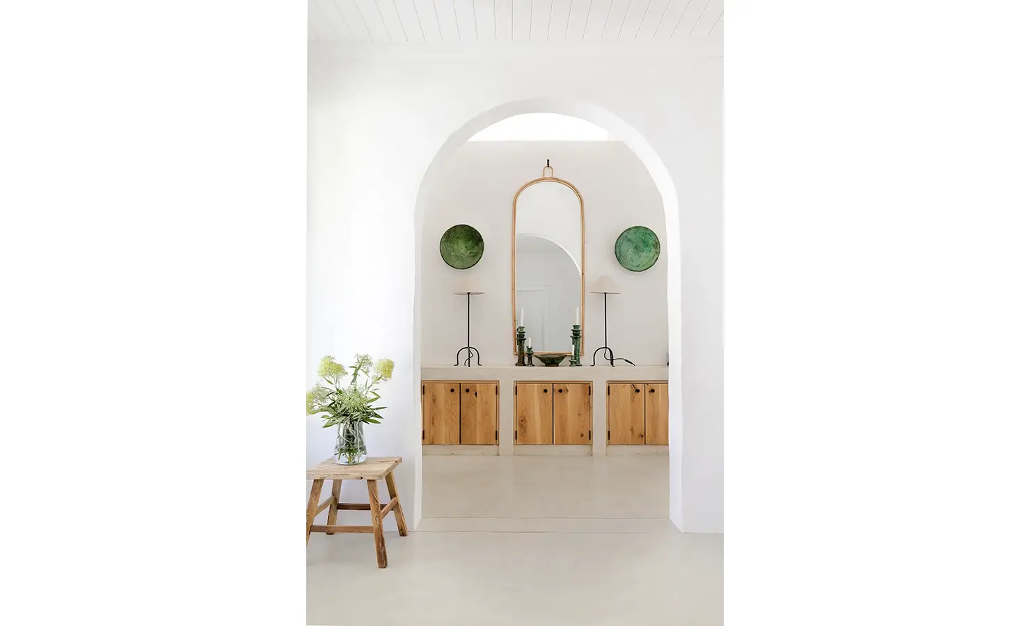 Buchubos Villa with large white arches that exposes a built in cabinet and large mirror.