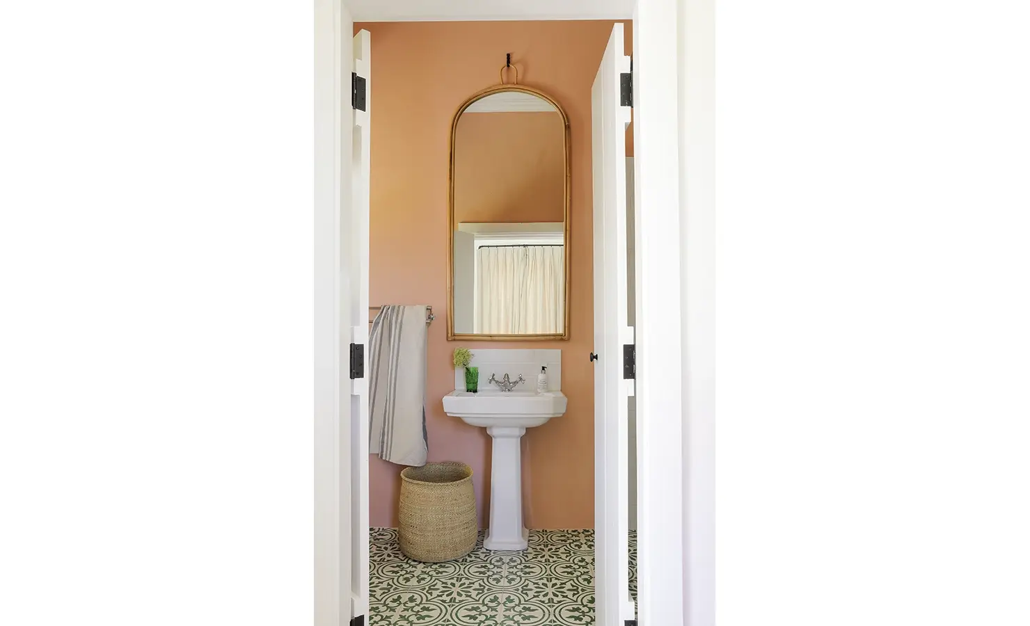 Buchubos Villa bathroom with orange wall, decorative flooring, a ceramic washbasin and mounted wall mirror.