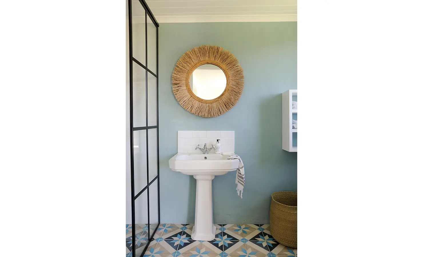 Bathroom with blue walls and a white ceramic washbasin and glass shower.