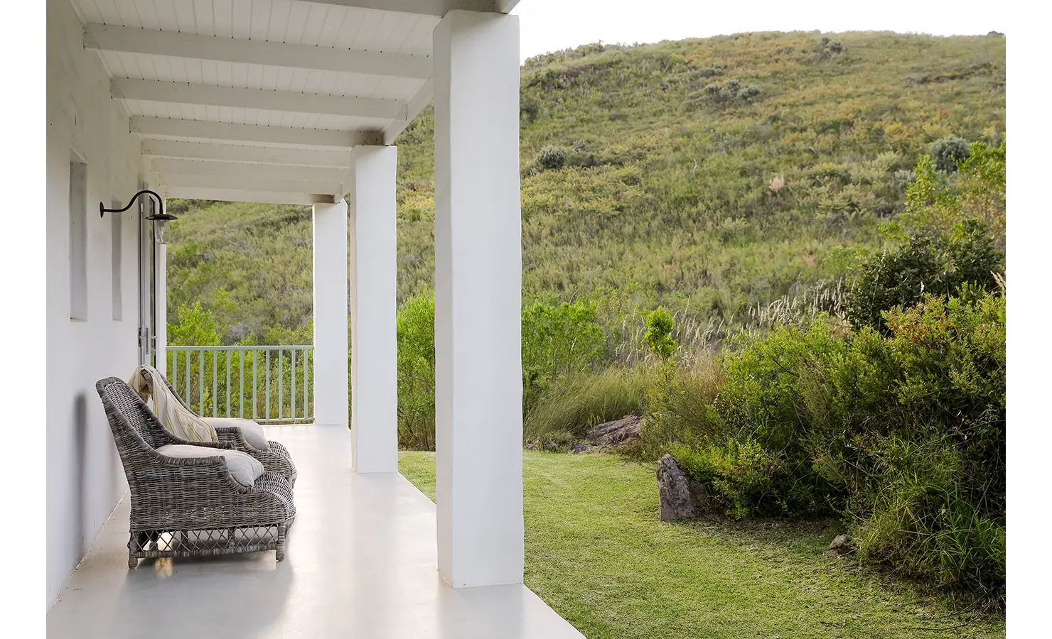 Buchubos villa verandah with large wicker armchairs facing the green landscape.