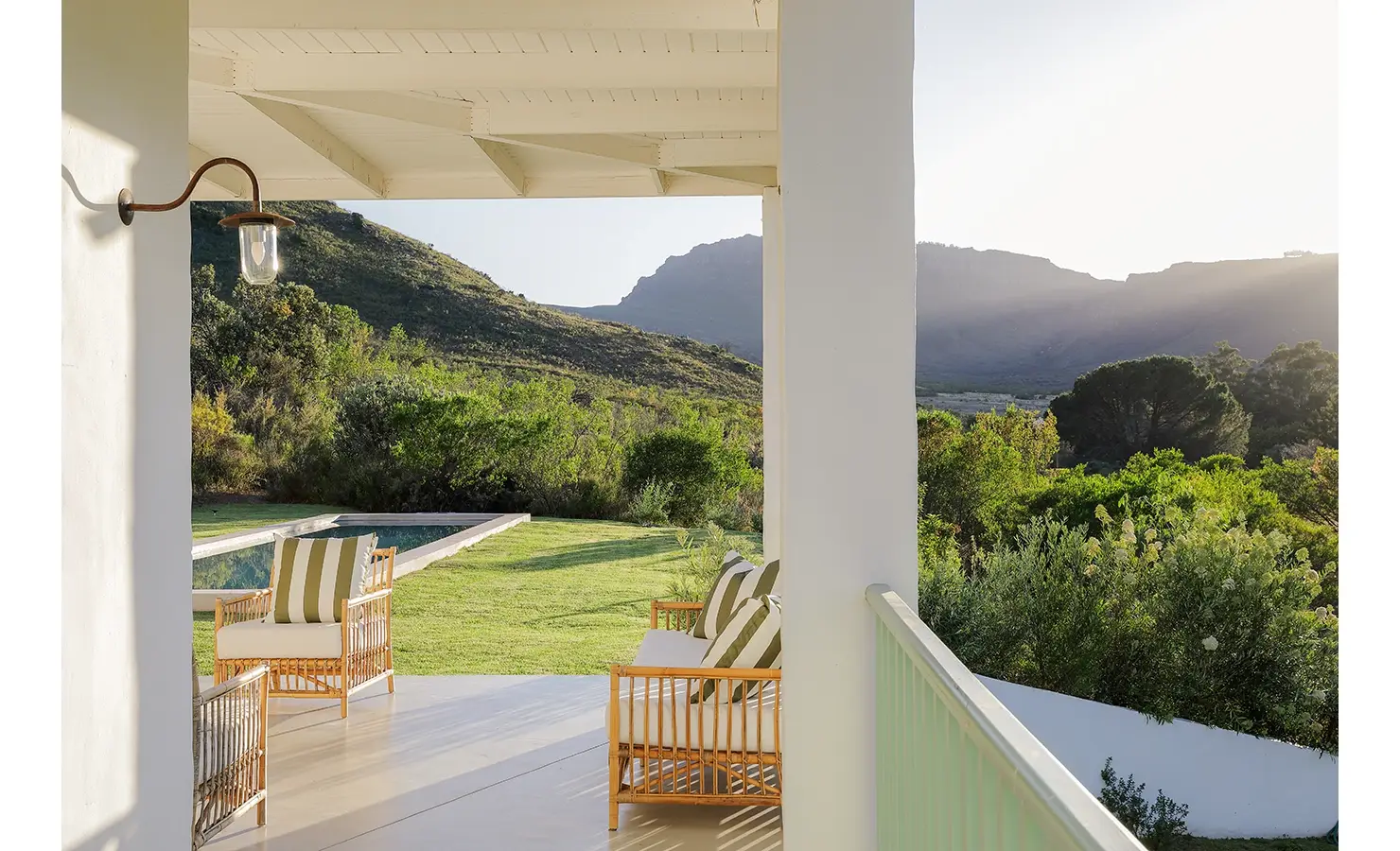 Wrap around verandah with white cushioned wicker sofa and armchairs overlooking at Buchubos Villa garden and swimming pool.