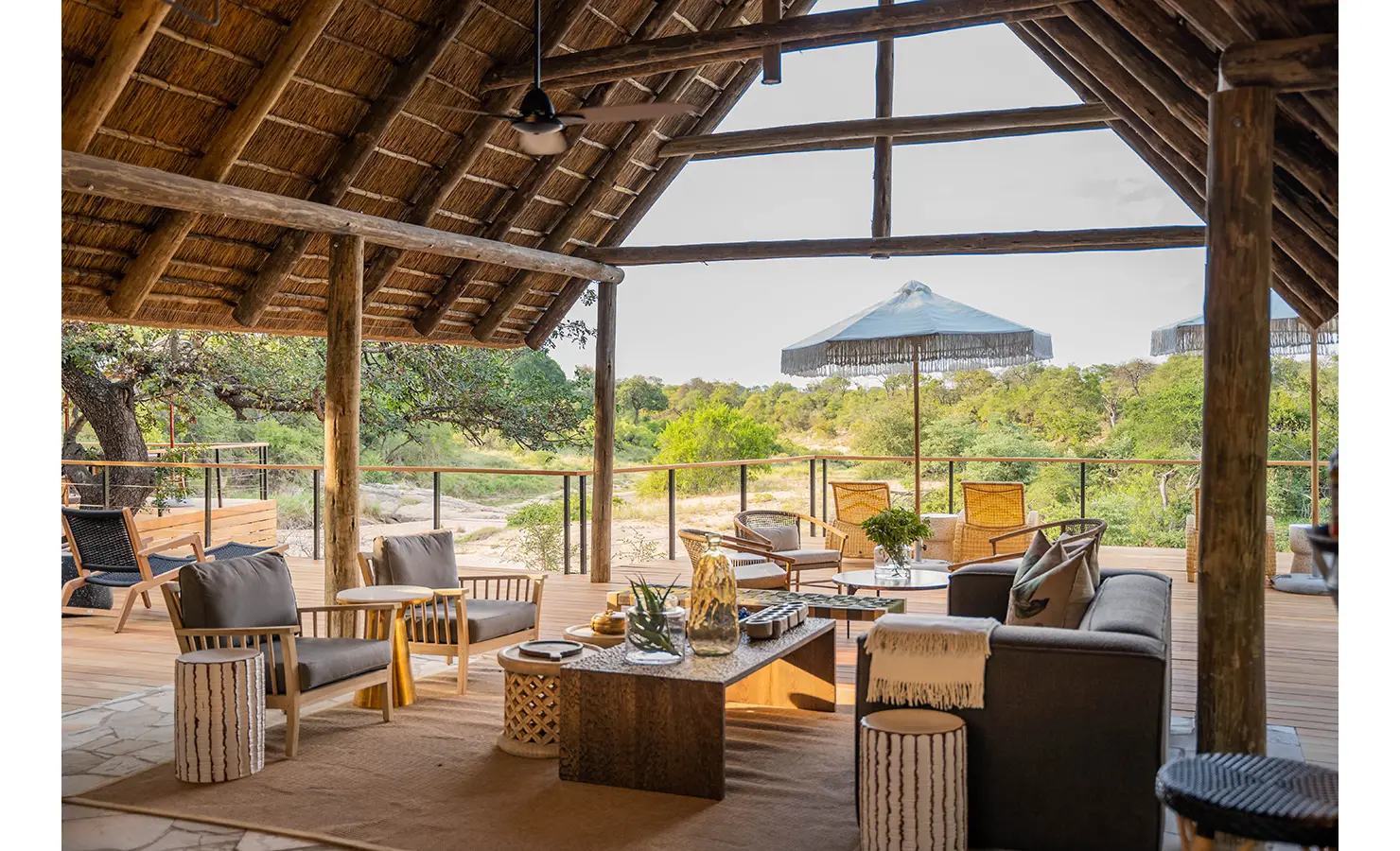Perfect Hideaways: A stylish bar and lounge area under a thatched roof, adorned with woven light fixtures and comfortable seating. The lodge’s warm and inviting decor combines natural textures with contemporary elegance. Thornybush Lodge, Thornybush Game Reserve.