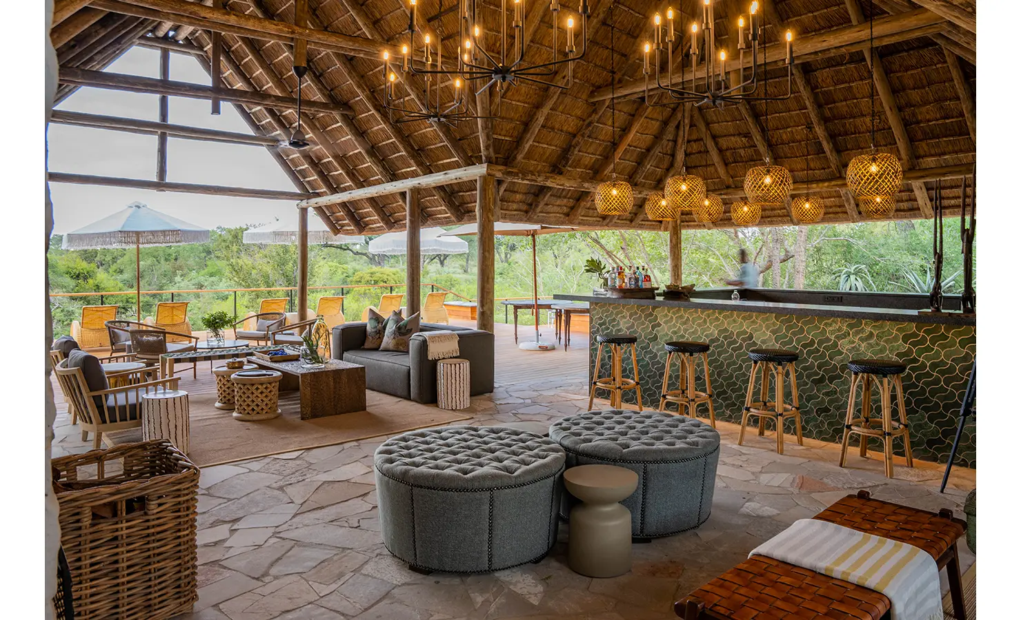 Perfect Hideaways: A cosy, intimate lounge nook with plush seating, soft textiles, and earthy tones. The rustic stone wall and thatched roof enhance the lodge’s warm and authentic safari aesthetic. Thornybush Lodge, Thornybush Game Reserve.