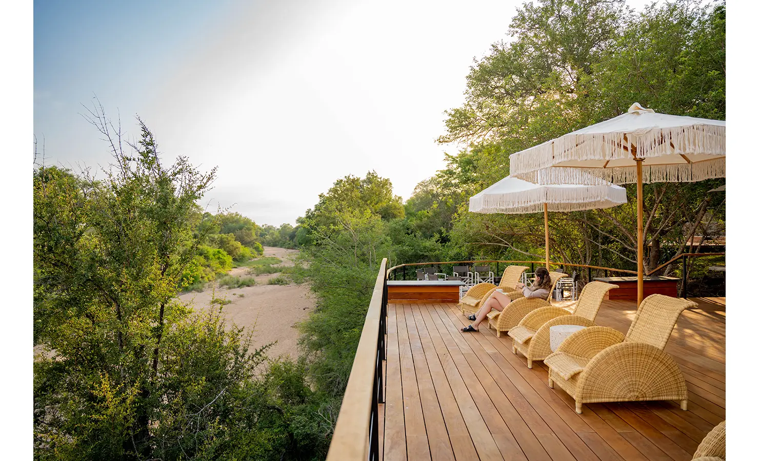 Perfect Hideaways: The lodge’s open-air dining area, set beneath a traditional thatched roof and surrounded by ancient trees. Wooden tables and woven pendant lights create an elegant yet relaxed setting for enjoying meals under the African sky. Thornybush Lodge, Thornybush Game Reserve.