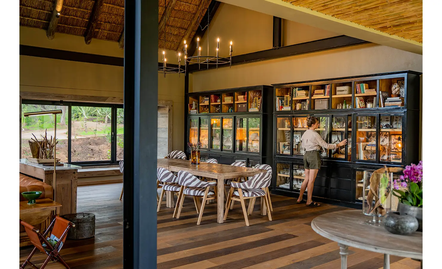 Perfect Hideaways: A peaceful sun deck overlooking the dry riverbed, where guests can lounge on woven daybeds under fringed umbrellas. The uninterrupted views of the wilderness make this a perfect retreat for relaxation and wildlife spotting. Thornybush Lodge, Thornybush Game Reserve.