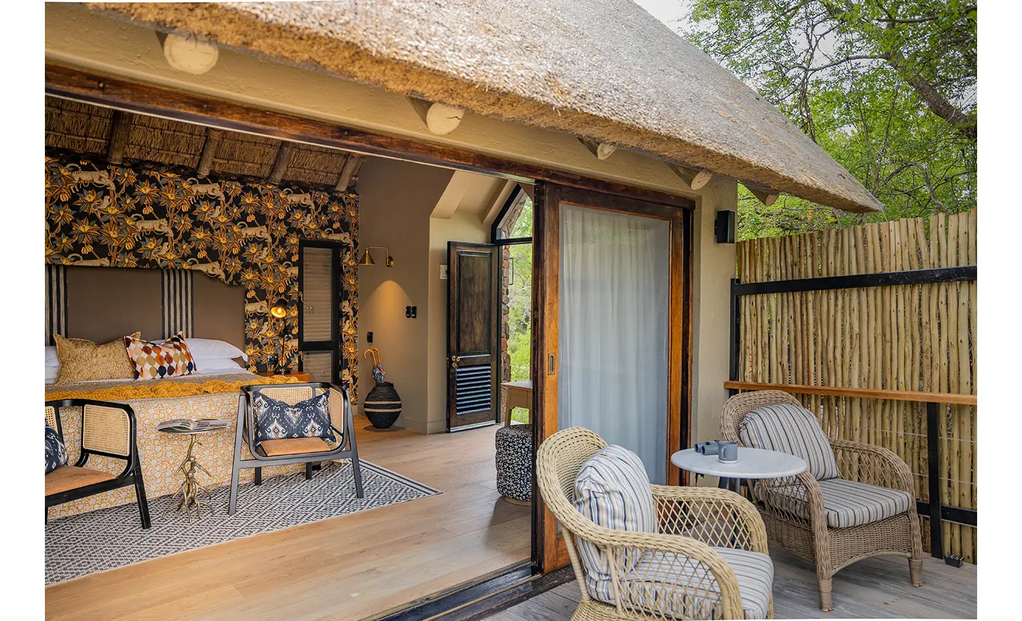 Perfect Hideaways: A spacious bedroom at Thornybush Lodge, with an intricately designed wooden ceiling, sliding glass doors opening onto a private deck, and rich, earthy decor reflecting the natural beauty of the African bushveld. Thornybush Lodge, Thornybush Game Reserve.