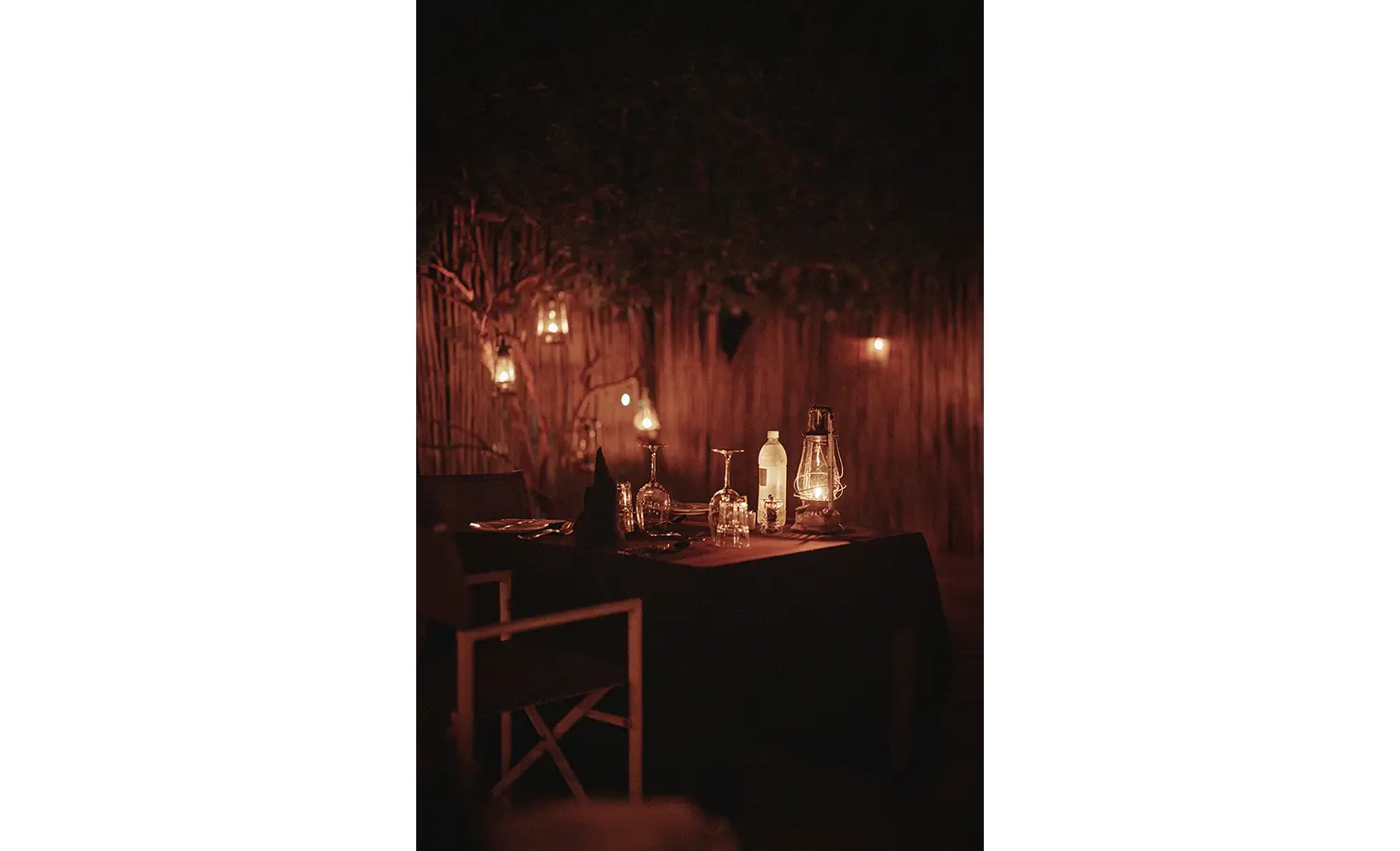 Perfect Hideaways: A magical lantern-lit dinner setting, tucked away in a private boma under the night sky. The flickering glow of oil lamps creates an intimate and romantic safari dining experience. Thornybush Lodge, Thornybush Game Reserve.