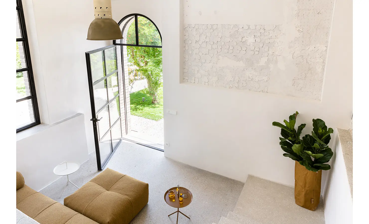 Perfect Hideaways: A welcoming living room with a glass door opening to a garden, a mustard-toned sofa, and a green potted plant adding vibrancy to the neutral tones. Umbria Cottage, Collazzone.
