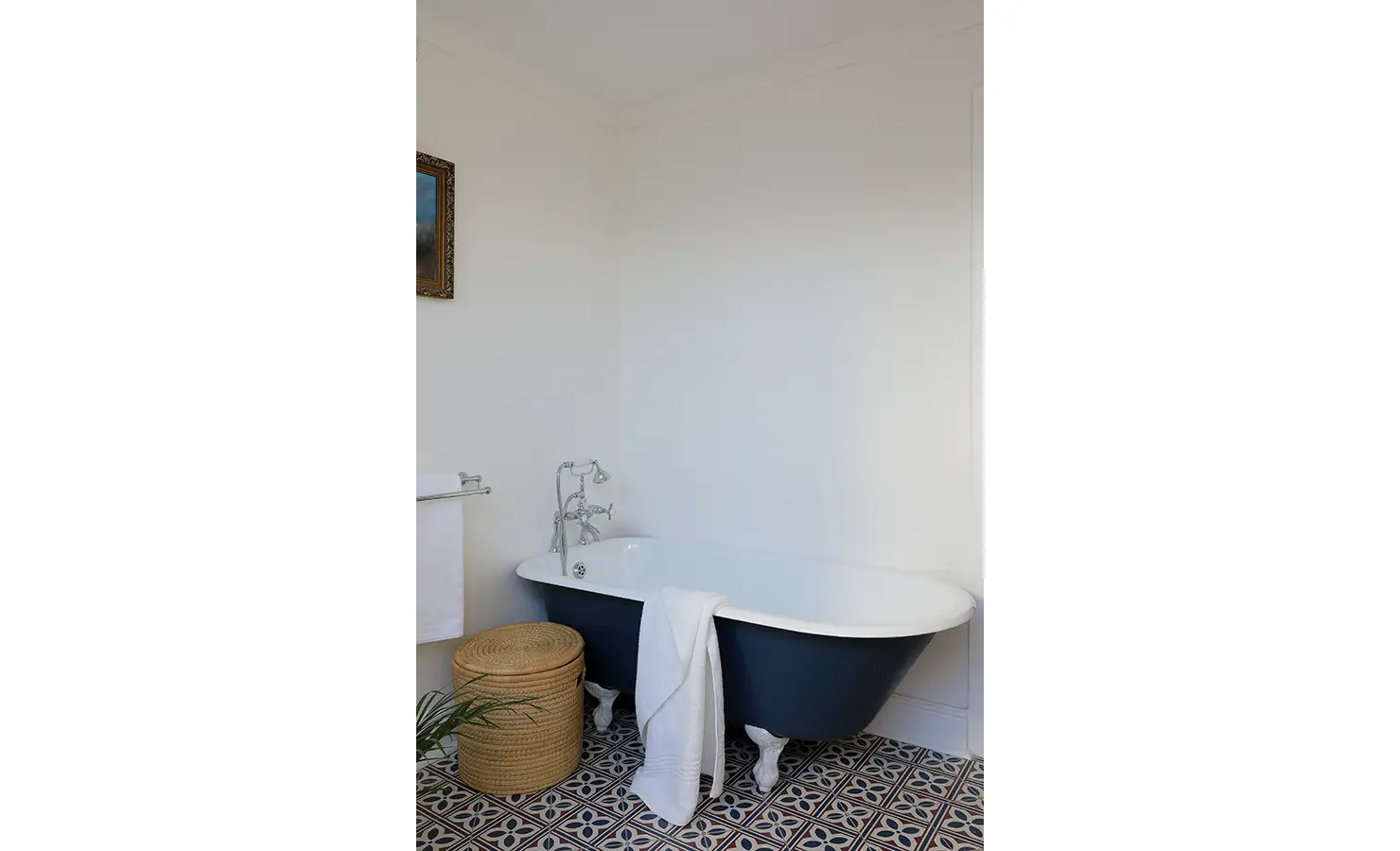 Perfect Hideaways: A stylish bathroom with a deep navy clawfoot bathtub, patterned floor tiles, and a classic chrome tap. The elegant yet understated design makes for a perfect sanctuary. Boulders House, Simons Town.