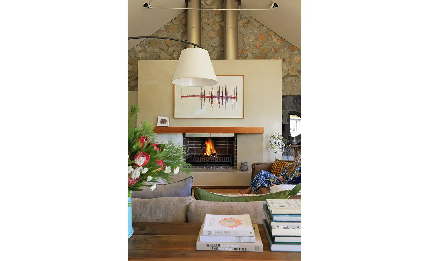Perfect Hideaways: Warm and inviting lounge with a roaring fire in the stone hearth and modern art above the mantel. Stonehaven House, Hemel-en-Aarde.