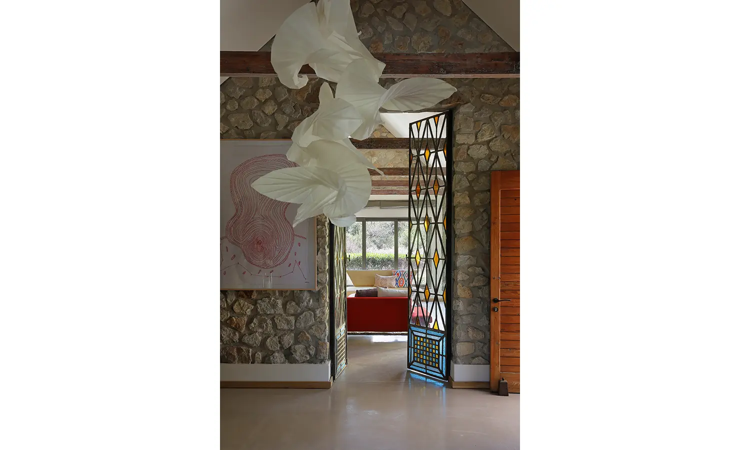 Perfect Hideaways: Entrance hall with textured stone walls, striking sculptural light fitting, and decorative wrought-iron doors. Stonehaven House, Hemel-en-Aarde.