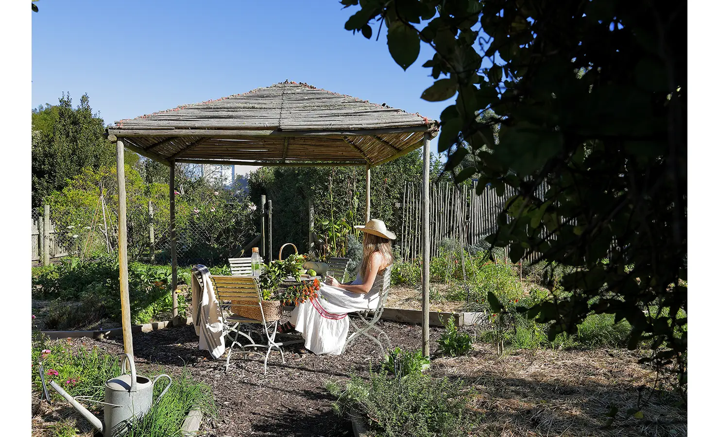 Perfect Hideaways: Shaded garden pergola with rustic seating where a guest relaxes among the vegetable beds. Stonehaven House, Hemel-en-Aarde.