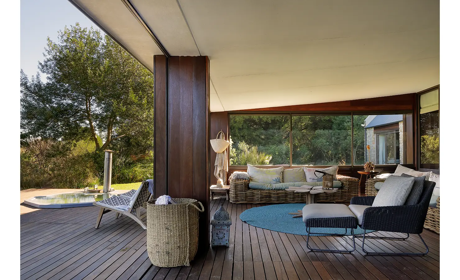 Perfect Hideaways: Covered wooden deck with wicker sofas, woven basket accents, and serene views of the natural surroundings. Stonehaven House, Hemel-en-Aarde.