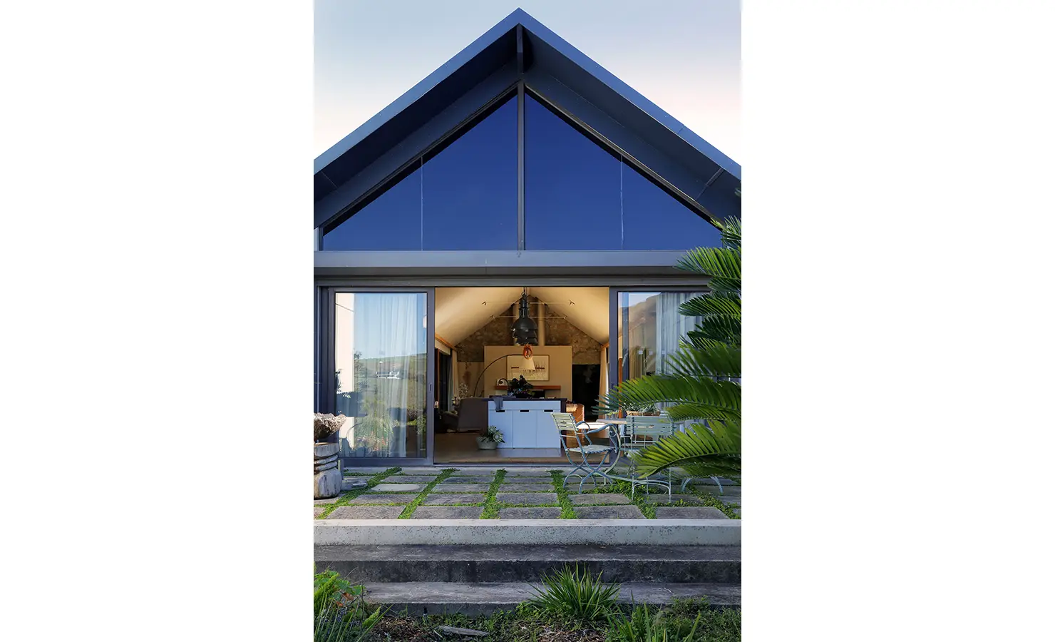 Perfect Hideaways: Modern gabled house exterior with floor-to-ceiling glass doors opening into a welcoming living space. Stonehaven House, Hemel-en-Aarde.