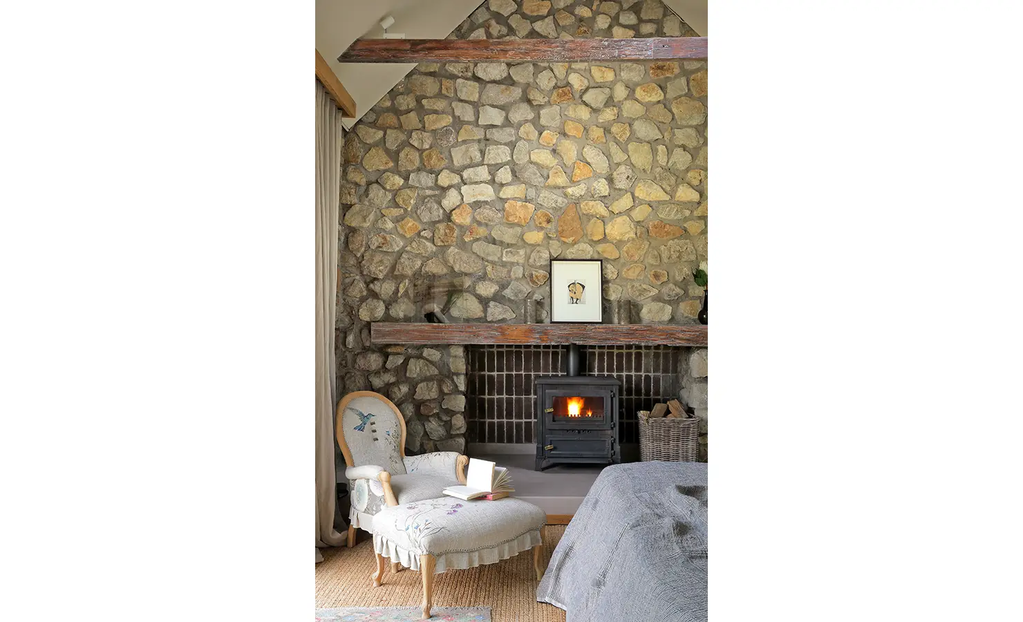 Perfect Hideaways: Cosy bedroom corner with fireplace, stone wall, and upholstered armchair perfect for reading. Stonehaven House, Hemel-en-Aarde.