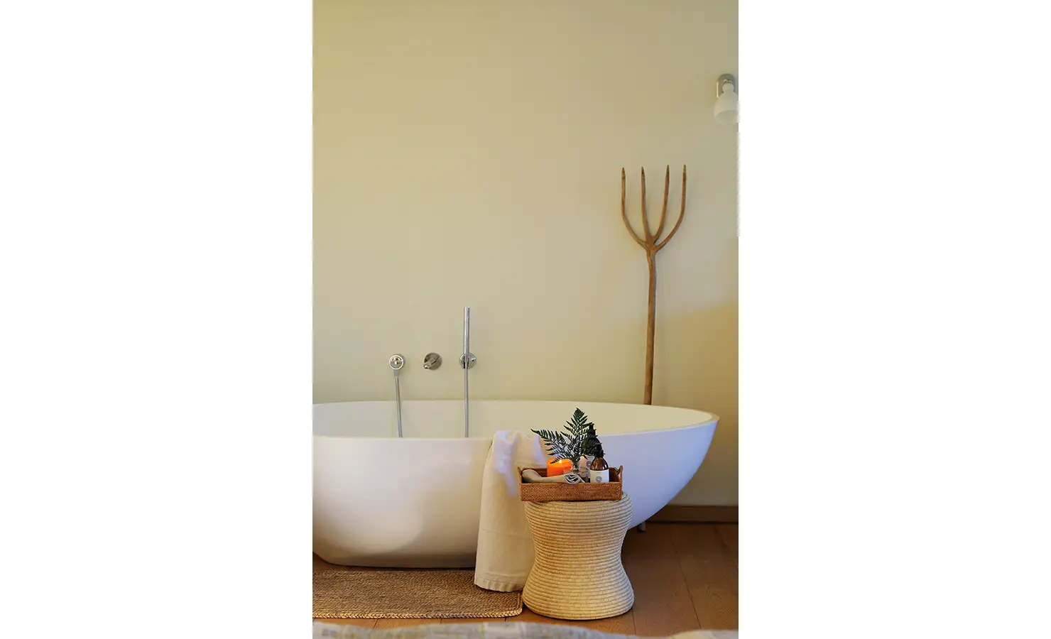 erfect Hideaways: Minimalist bathroom with freestanding tub, woven basket of bath essentials, and rustic wooden pitchfork accent. Stonehaven House, Hemel-en-Aarde.