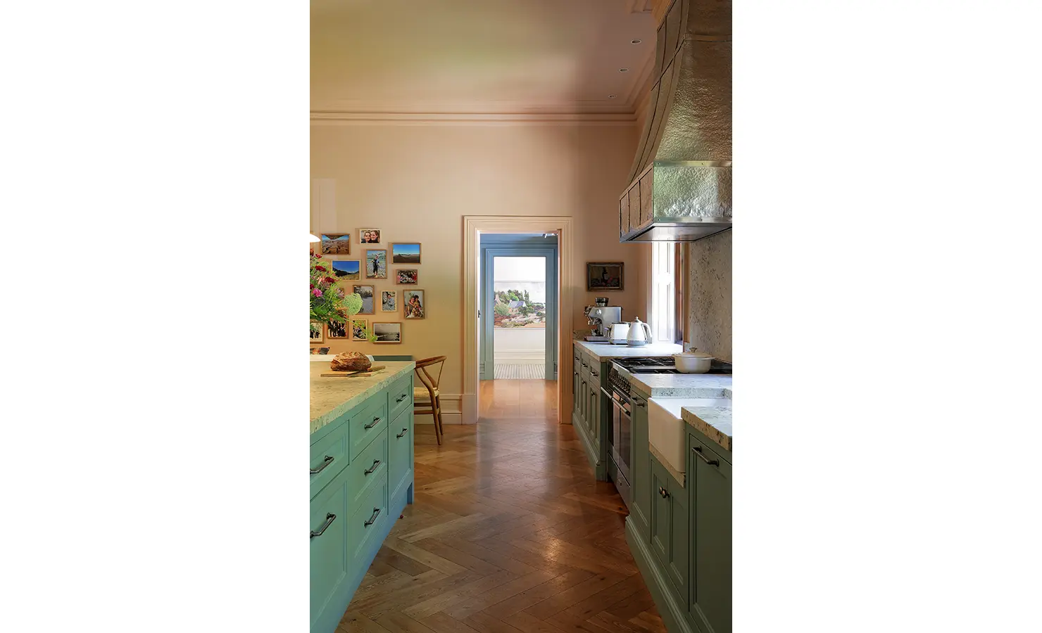 Perfect Hideaways — A bright, airy kitchen with mint-green cabinetry, marble countertops, and warm wooden floors. The space leads through to a hallway adorned with framed photos and art, blending classic and modern design. Bishopscourt, Bishops Hall.