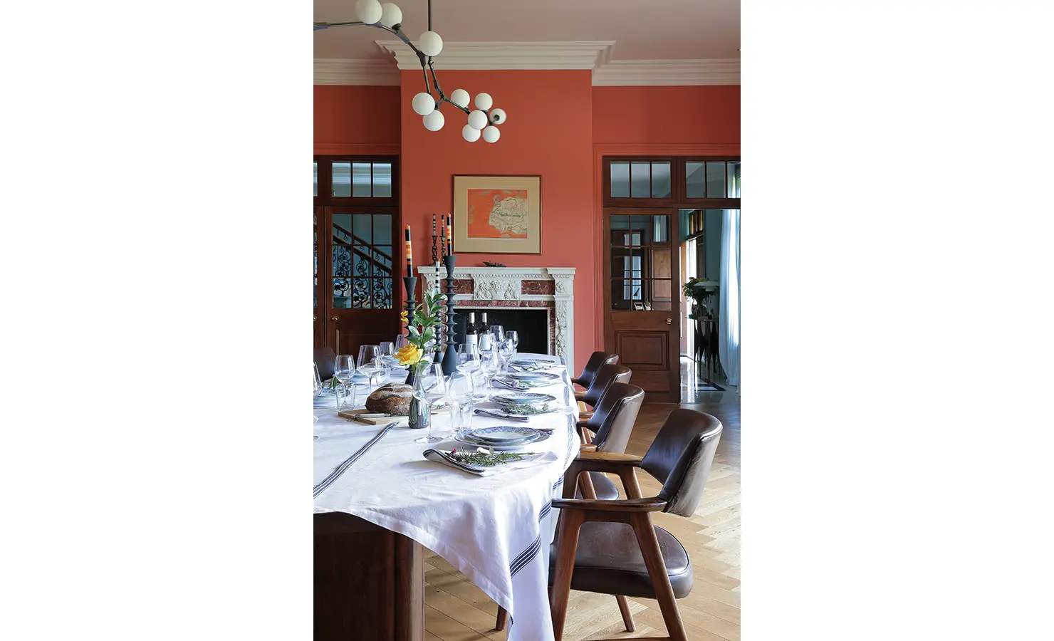 Perfect Hideaways — A refined dining space with coral-painted walls, a white marble fireplace, and a beautifully arranged table set with glassware and floral accents. Modern lighting adds a touch of contemporary elegance. Bishopscourt, Bishops Hall.